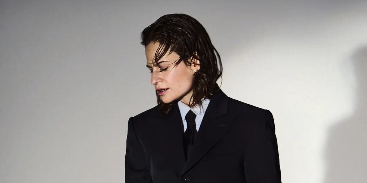 Christine and the Queens wearing a dark suit in an official publicity photograph.